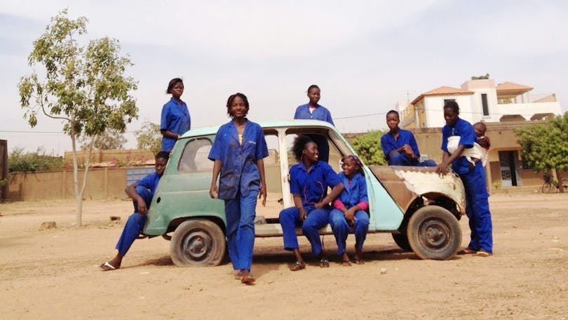 Från Ouaga Girls, en dokumentärfilm av Theresa Traore Dahlberg. Kvinnorna står i blåa arbetskläder utomhus runt en turkos bil. 