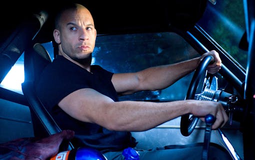 Dominic Toretto (Vin Diesel) spänner musklerna bakom ratten på en muskelbil. Foto: Universal Pictures.