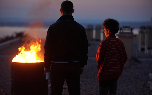 Dali Benssalah och Maël Rouin Berrandou står med ryggarna vända mot kameran framför en levande eld i Mina bröder och jag (2021).