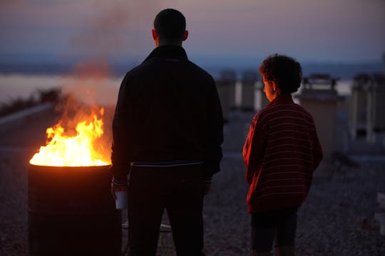 Dali Benssalah och Maël Rouin Berrandou står med ryggarna vända mot kameran framför en levande eld i Mina bröder och jag (2021).